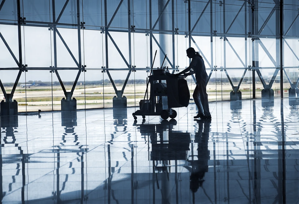 Scène intérieure d'aéroport avec agent d'entretien utilisant une autolaveuse sur sol carrelage brillant